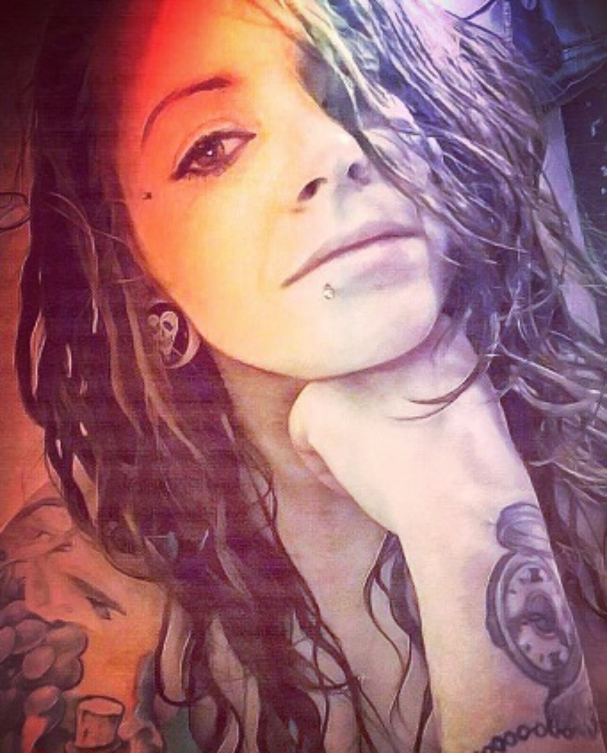 CJ, the artist behind CJT Creations, with wavy hair, skull earrings, and arm tattoos